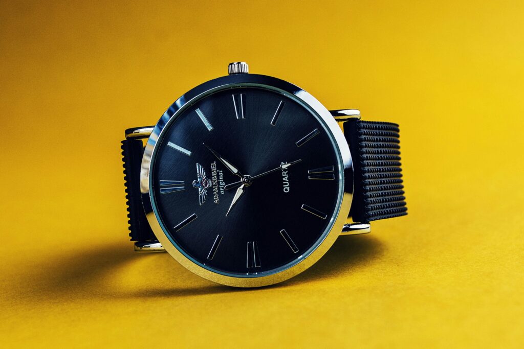 Gros plan d’une montre noire sur fond jaune, rappelant le design minimaliste et les détails du cadran