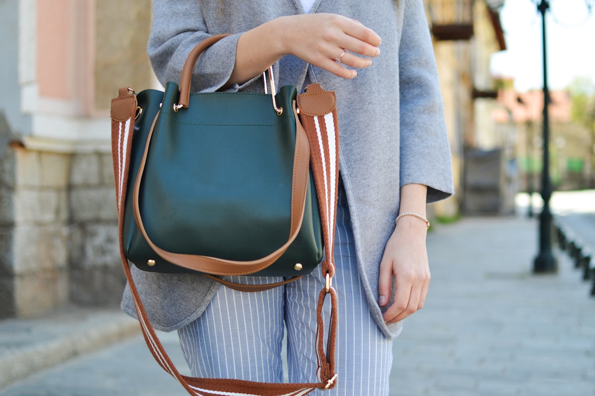 Sustainable luxury leather brands — artisan hands stitching full-grain leather in an ethical workshop
