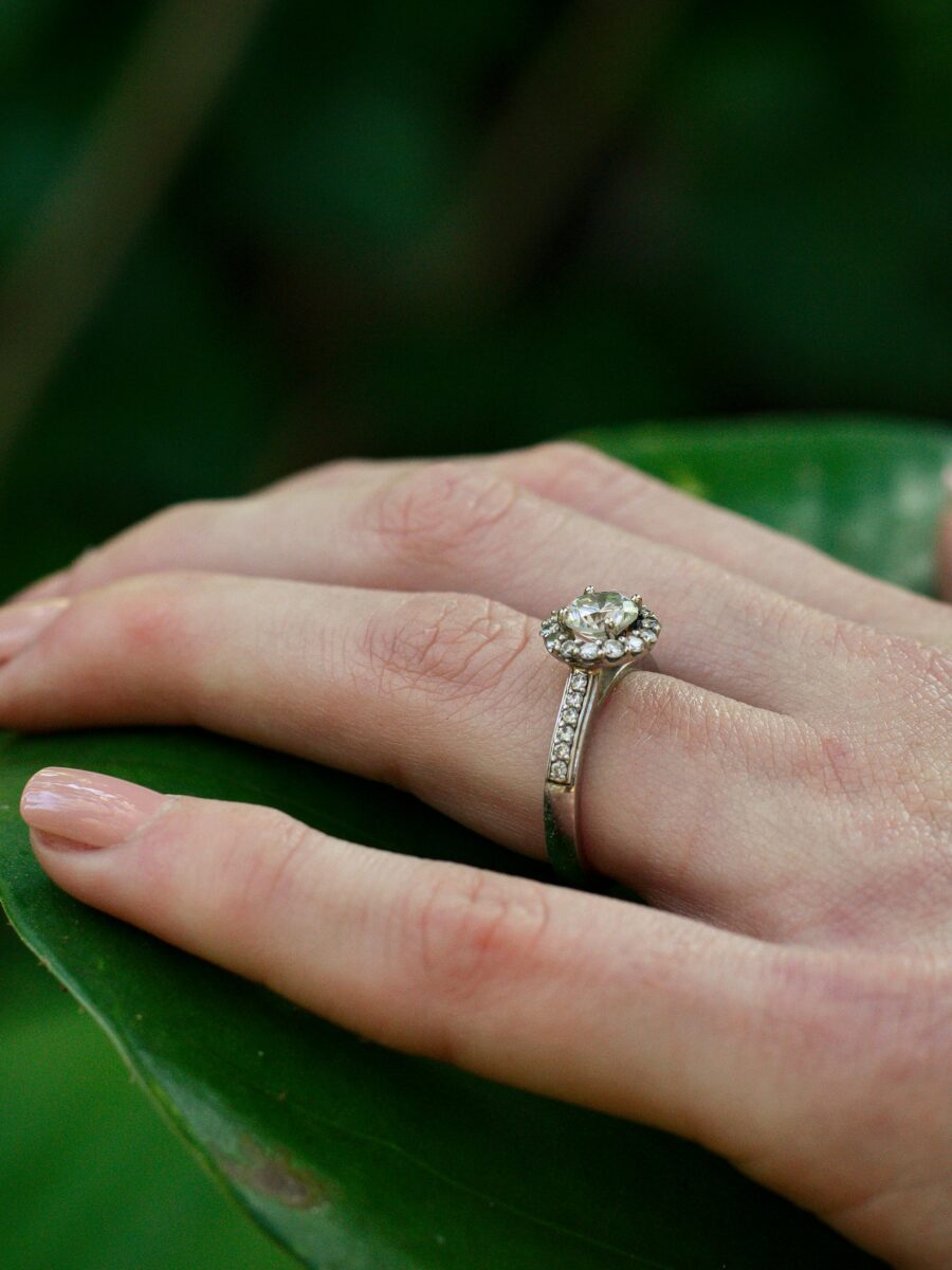 Diamond engagement ring on a hand against a natural background