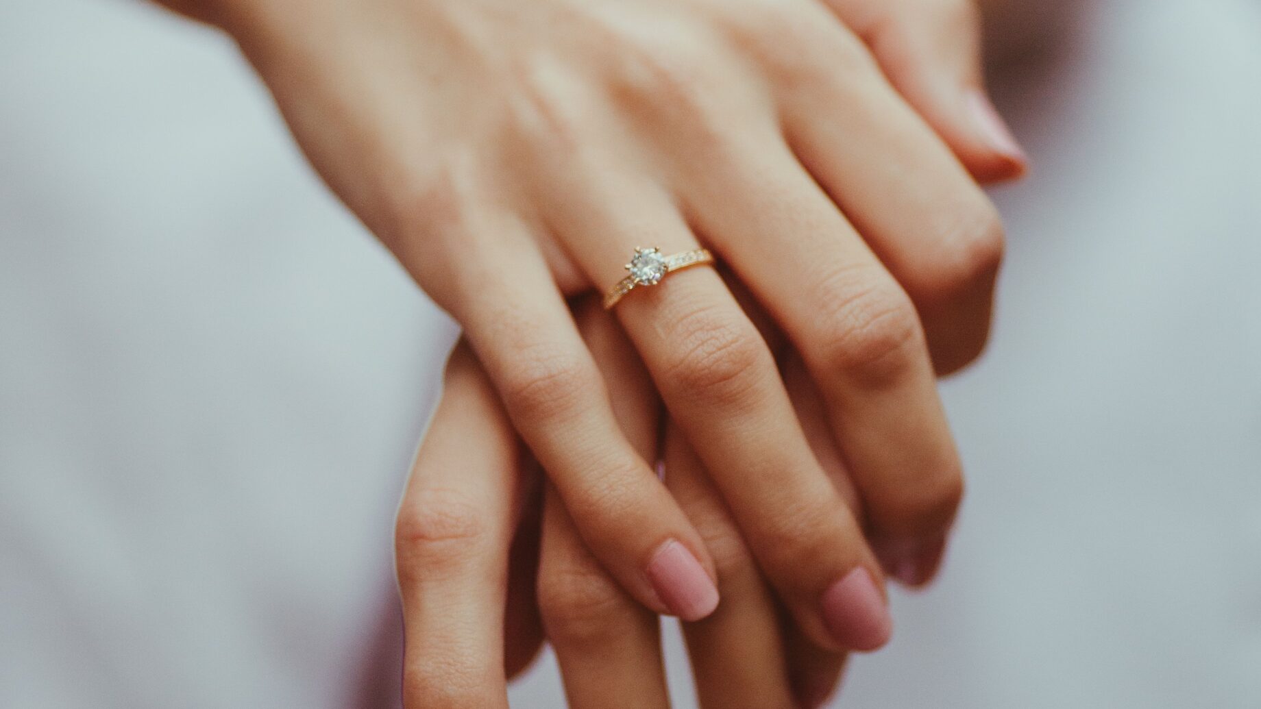 Diamond engagement ring on a woman's finger in soft natural light