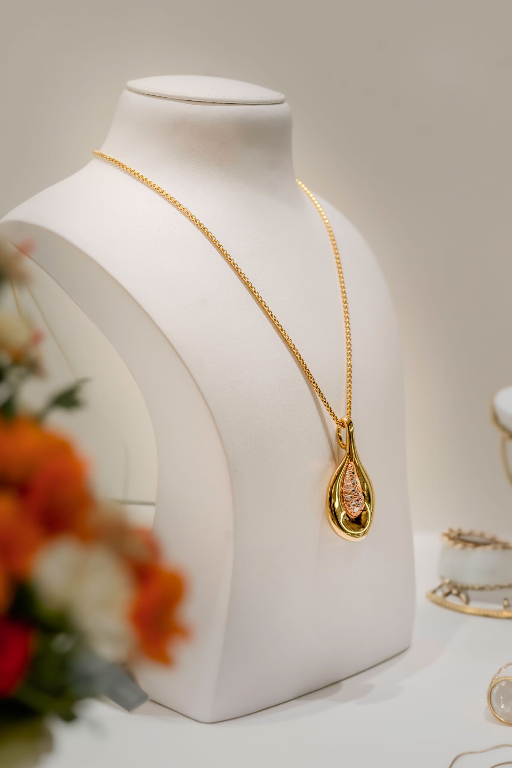 Collier pendentif en or présenté sur un buste à bijoux