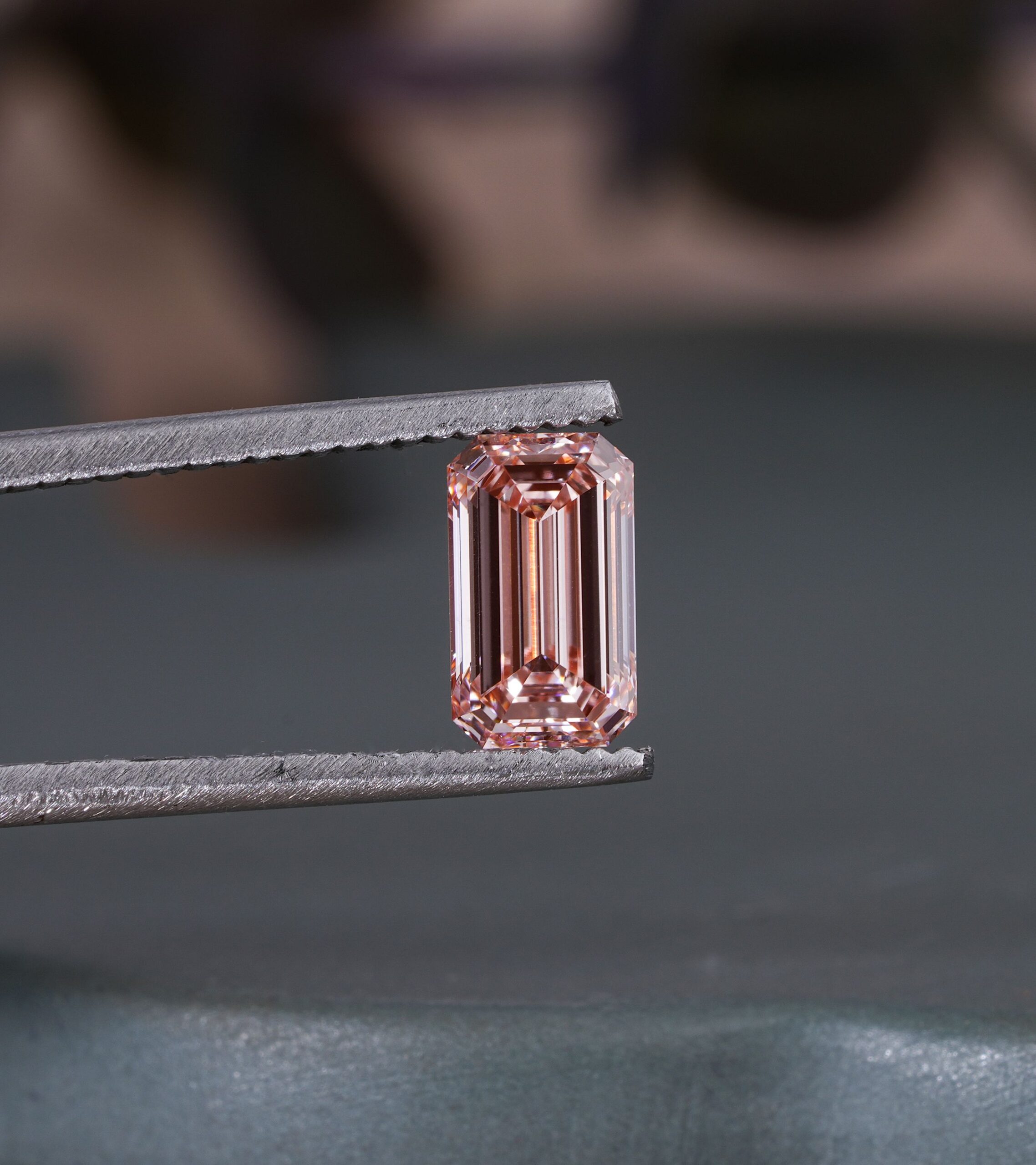 Diamant taille émeraude tenu dans une pince, montrant les facettes à degrés